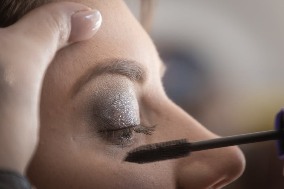 A woman's eyelid is delicately painted with glamorous shimmery eyeshadow and mascara