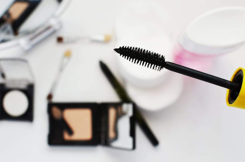 Flat lay of cosmetics featuring a mascara brush, perfect for beauty and fashion themes