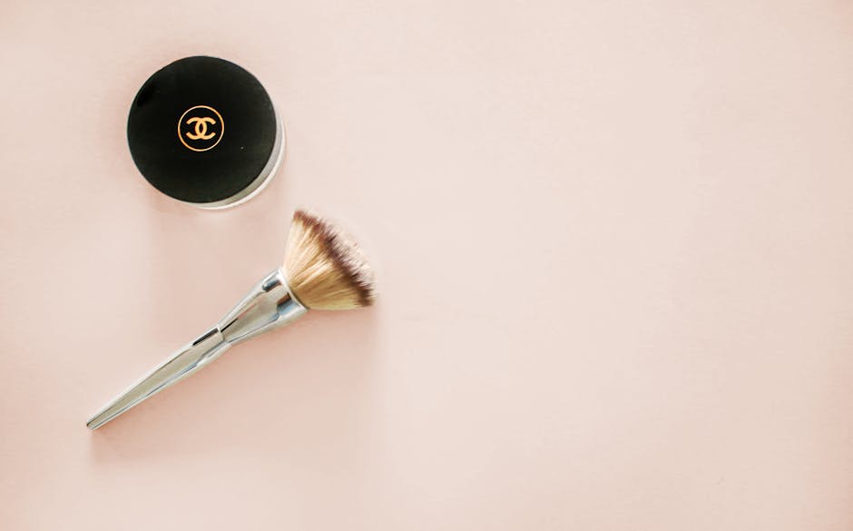 Sophisticated flatlay of a makeup brush and branded cosmetic jar on a pastel background.