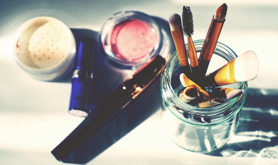 Artistic flat lay of makeup brushes in a jar surrounded by colorful cosmetics, perfect for beauty themes